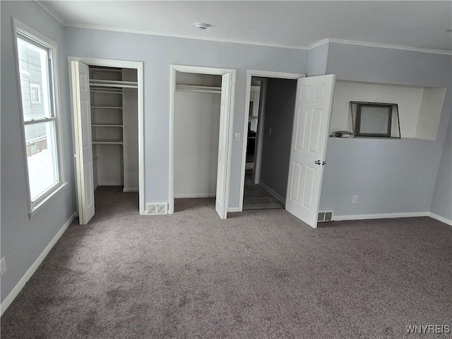 unfurnished bedroom featuring visible vents, carpet flooring, baseboards, and multiple closets