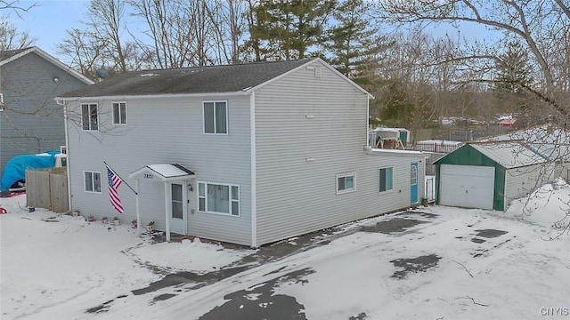 view of snow covered exterior with a detached garage and an outdoor structure