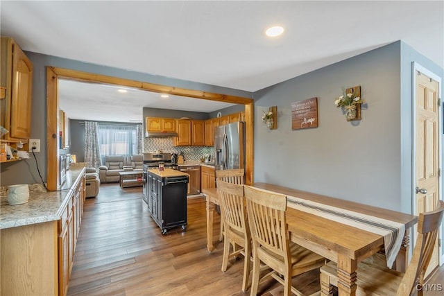 kitchen featuring brown cabinetry, light wood-style flooring, stainless steel appliances, light countertops, and tasteful backsplash