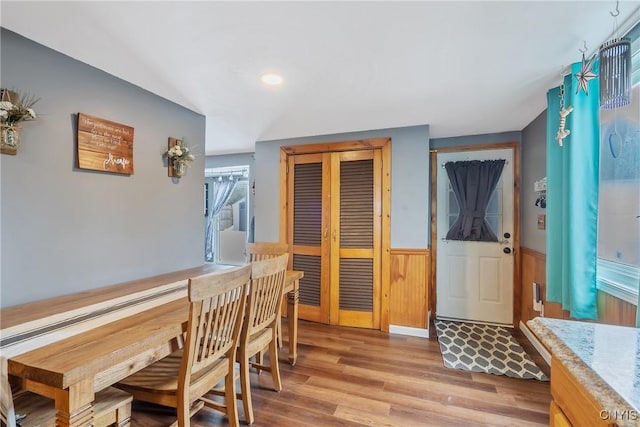 dining area with light wood finished floors and wainscoting