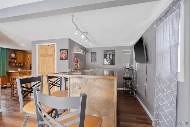 bar featuring visible vents, baseboards, rail lighting, wood finished floors, and a bar