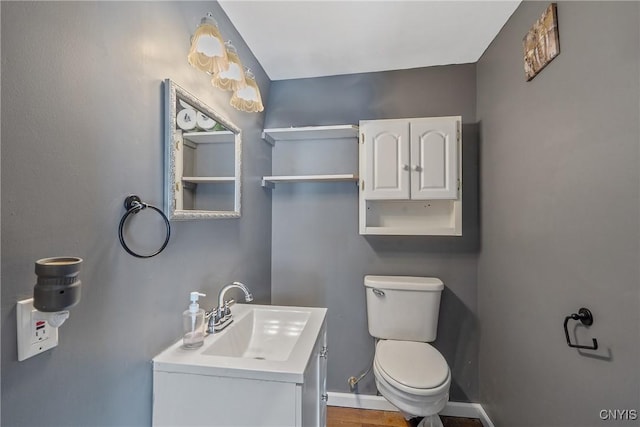 bathroom featuring toilet, vanity, and baseboards