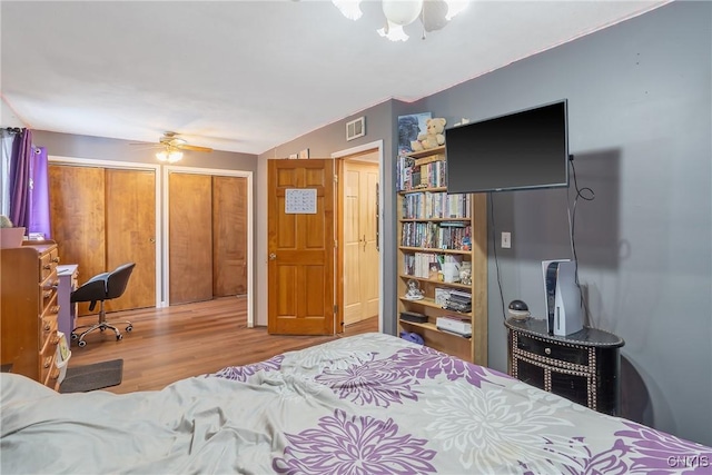 bedroom with ceiling fan, visible vents, and wood finished floors