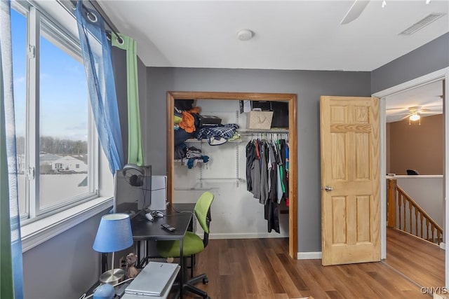 home office with a ceiling fan, wood finished floors, visible vents, and baseboards