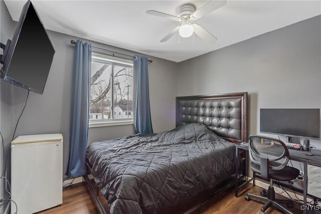 bedroom with a ceiling fan, refrigerator, and wood finished floors