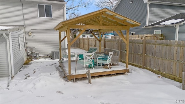 snow covered patio with a gazebo, cooling unit, a wooden deck, and fence