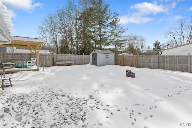 yard covered in snow with an outbuilding, a fenced backyard, and a shed