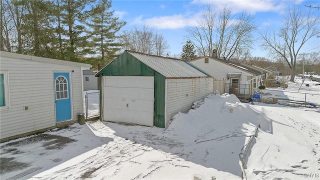 snow covered garage featuring a garage and fence