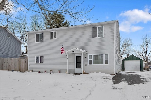 view of front of house with a detached garage, an outbuilding, and fence