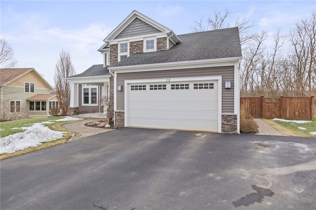 view of front of property with fence, a shingled roof, a garage, stone siding, and aphalt driveway