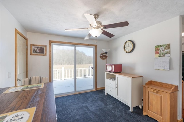 interior space featuring a ceiling fan, dark colored carpet, and a textured ceiling