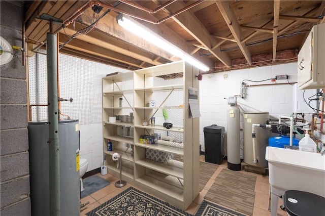 unfinished below grade area with water heater, light tile patterned floors, concrete block wall, and a sink