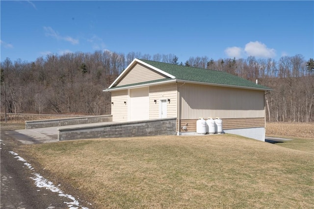 view of front of property featuring a front lawn and a wooded view