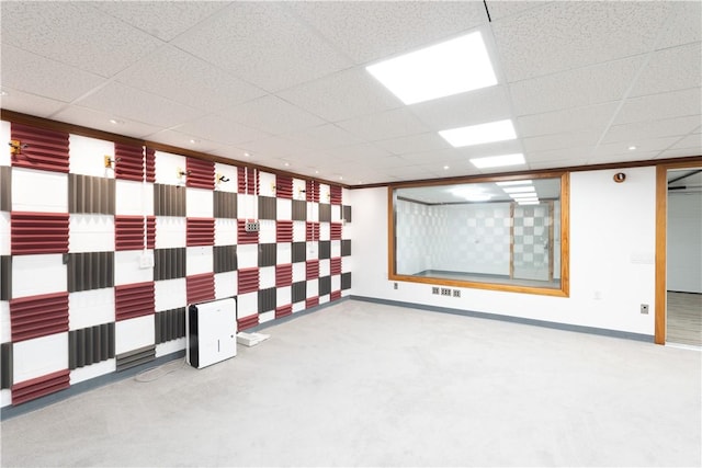 carpeted empty room with baseboards, visible vents, and a drop ceiling