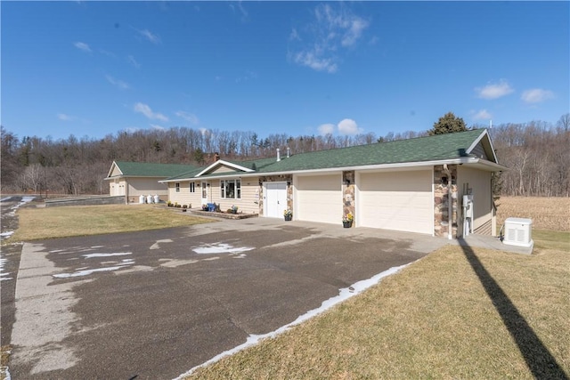 view of front facade with a garage, driveway, a front lawn, and stone siding