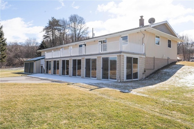 back of house with a balcony and a lawn