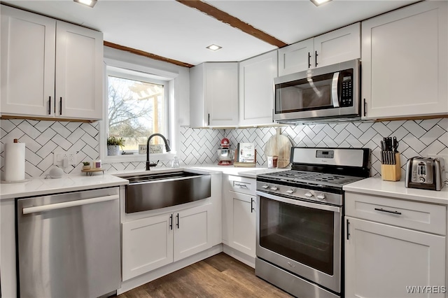 kitchen featuring a sink, wood finished floors, white cabinetry, stainless steel appliances, and light countertops