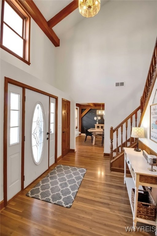 entrance foyer featuring stairway, a notable chandelier, a high ceiling, and wood finished floors