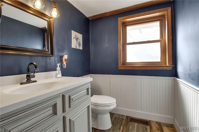 bathroom with visible vents, toilet, wainscoting, wood finished floors, and vanity