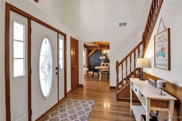 entrance foyer with visible vents, plenty of natural light, stairway, and wood finished floors