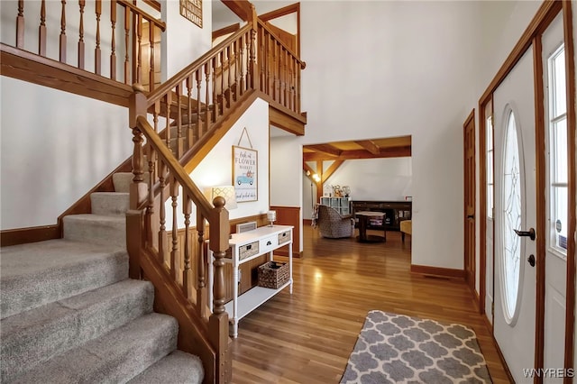 entryway featuring stairway, wood finished floors, and a towering ceiling