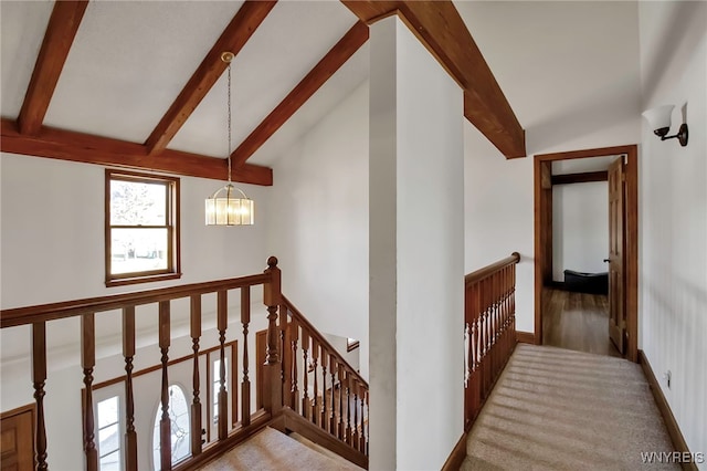 hallway featuring an upstairs landing, a chandelier, lofted ceiling with beams, and baseboards