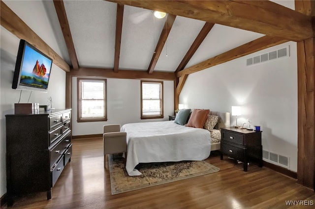 bedroom with lofted ceiling with beams, wood finished floors, and visible vents