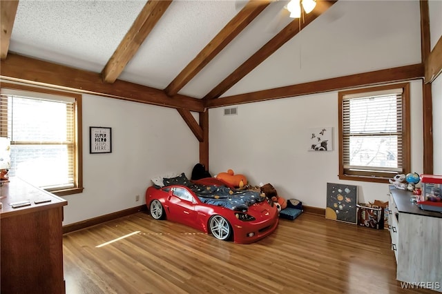 bedroom featuring visible vents, baseboards, wood finished floors, and vaulted ceiling with beams