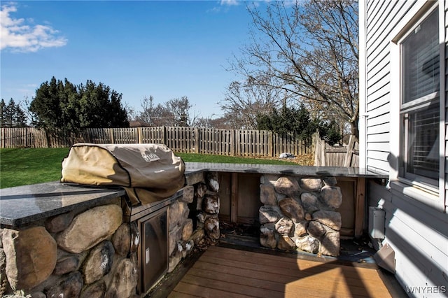 deck featuring an outdoor kitchen and a fenced backyard