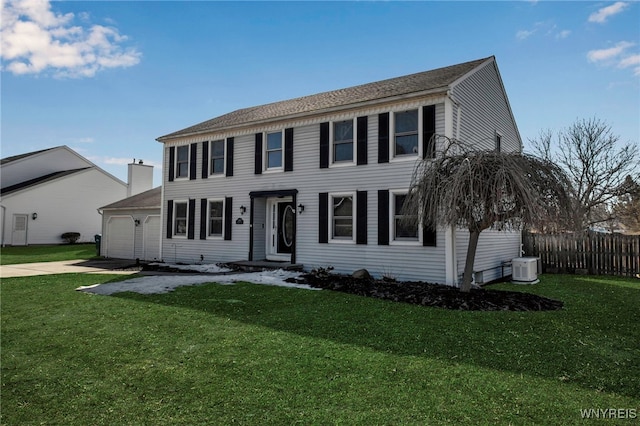 colonial-style house with a front lawn, fence, concrete driveway, central AC unit, and a garage