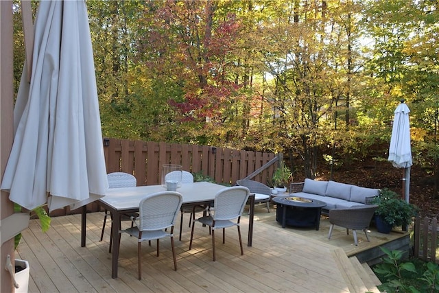 wooden deck with an outdoor living space with a fire pit, outdoor dining area, and fence