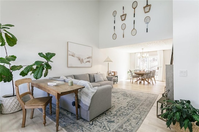 living area with a notable chandelier, a high ceiling, and wood finished floors