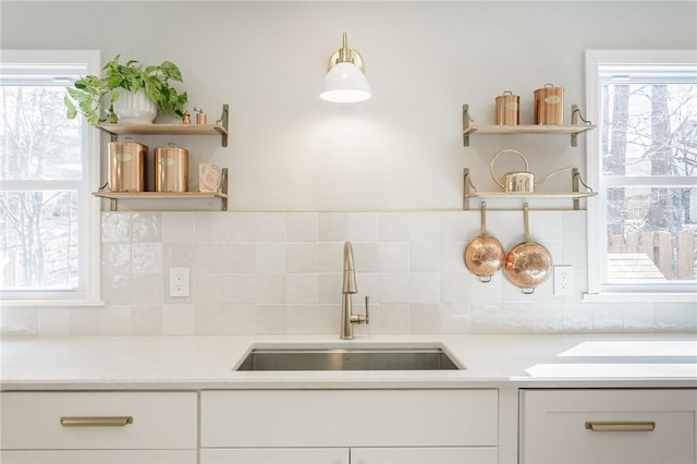 kitchen with open shelves, white cabinetry, light countertops, and a sink