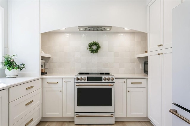 kitchen with white appliances, light wood-style flooring, light countertops, white cabinets, and backsplash