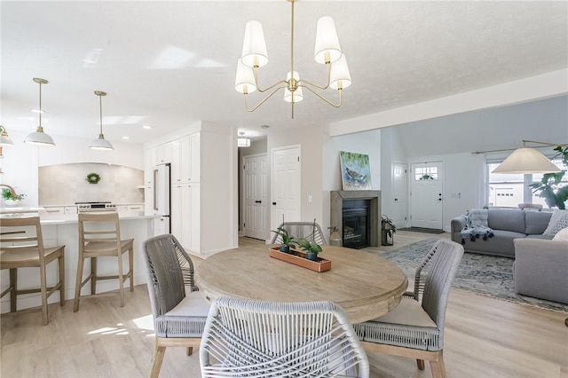 dining space with a glass covered fireplace, light wood-style flooring, and a chandelier