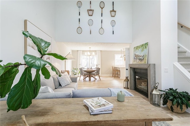 living area featuring a fireplace, stairs, a high ceiling, and wood finished floors