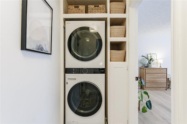 laundry room featuring wood finished floors, laundry area, and stacked washer / dryer