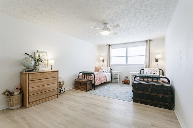 bedroom featuring a ceiling fan, wood finished floors, baseboards, and a textured ceiling