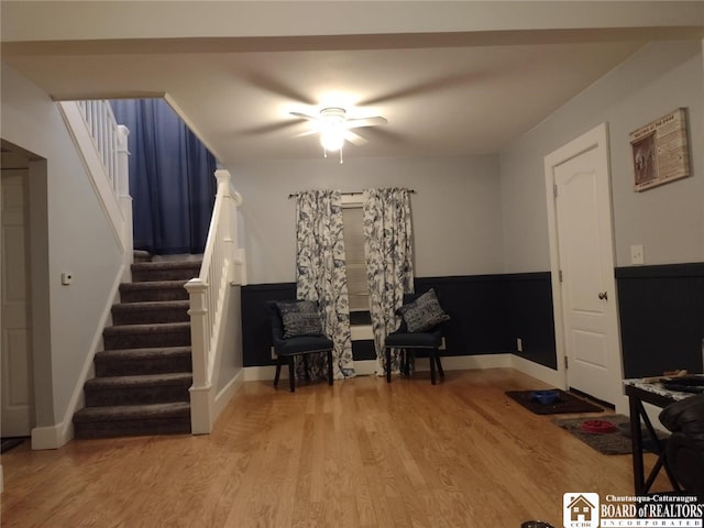 sitting room with stairs, wood finished floors, and baseboards