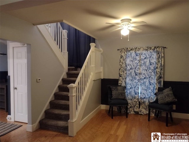 stairway with ceiling fan, baseboards, and wood finished floors