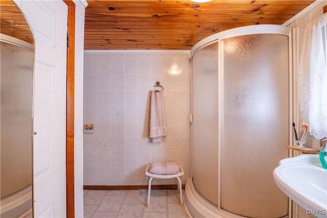 full bathroom with tile patterned floors, a stall shower, a sink, tile walls, and wood ceiling