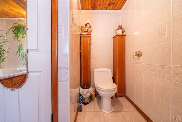 bathroom featuring tile patterned floors, toilet, and tile walls