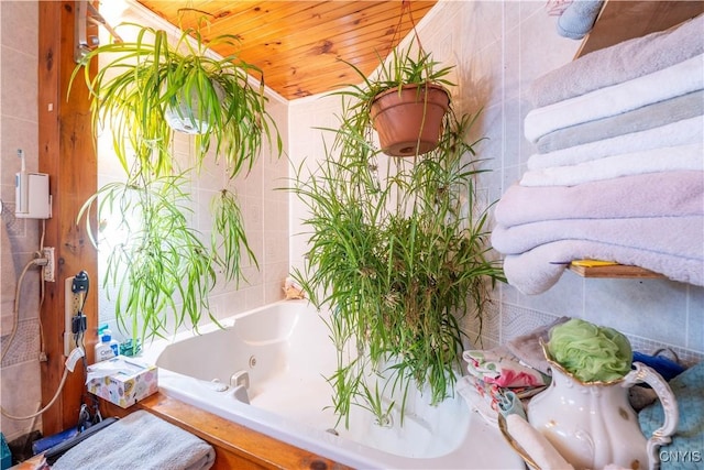 interior space with a tub with jets and wooden ceiling