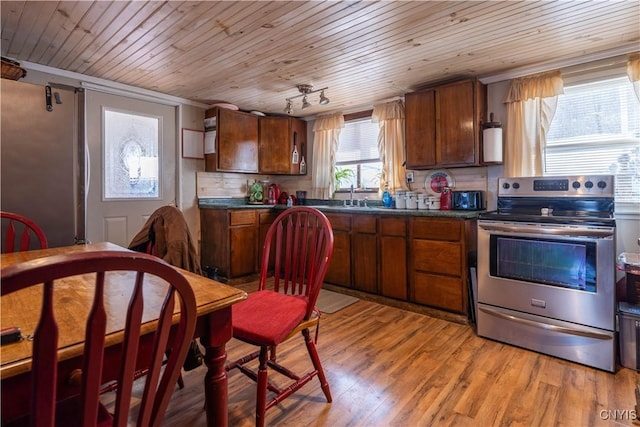 kitchen with dark countertops, stainless steel electric stove, backsplash, and light wood finished floors