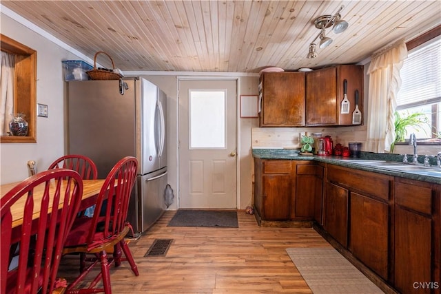 kitchen featuring visible vents, a sink, wood ceiling, dark countertops, and light wood-type flooring