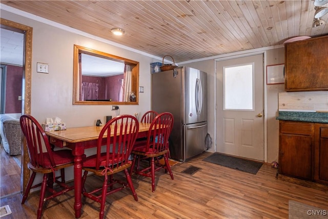 dining room with wood ceiling, wood finished floors, visible vents, and ornamental molding