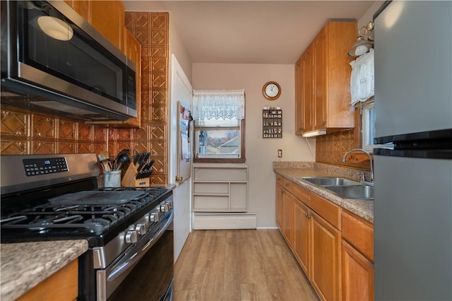 kitchen featuring tasteful backsplash, appliances with stainless steel finishes, brown cabinetry, and a sink