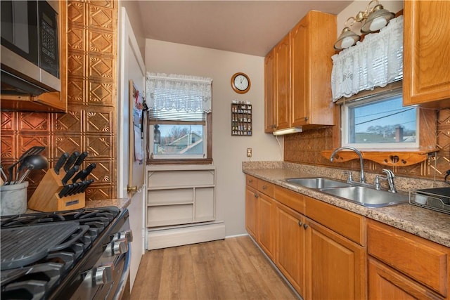 kitchen featuring light wood-type flooring, a sink, stainless steel appliances, tasteful backsplash, and brown cabinets