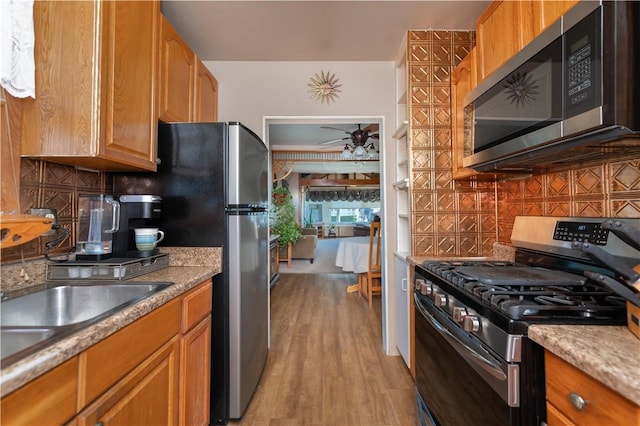 kitchen featuring decorative backsplash, ceiling fan, stainless steel appliances, and light wood-style floors