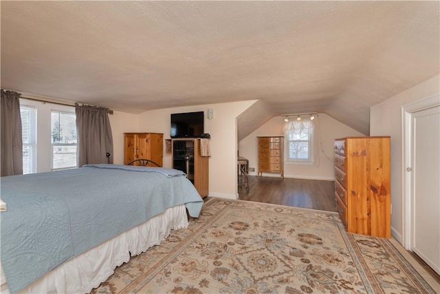 bedroom featuring vaulted ceiling, wood finished floors, and baseboards